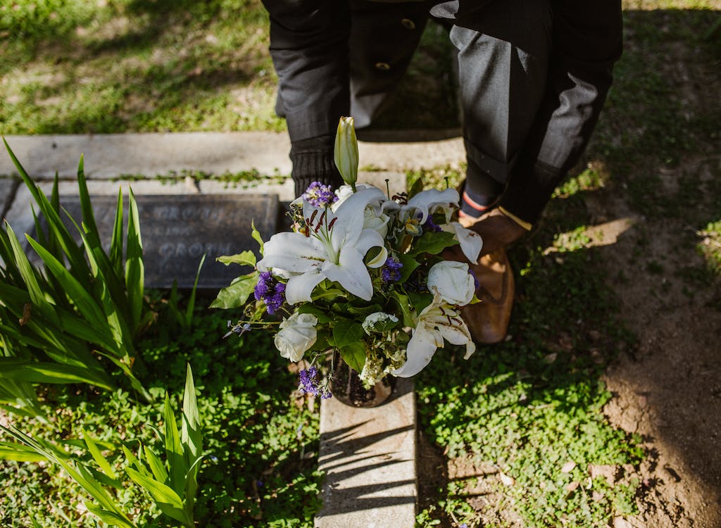 Close up of someone laying flowers at a grave.